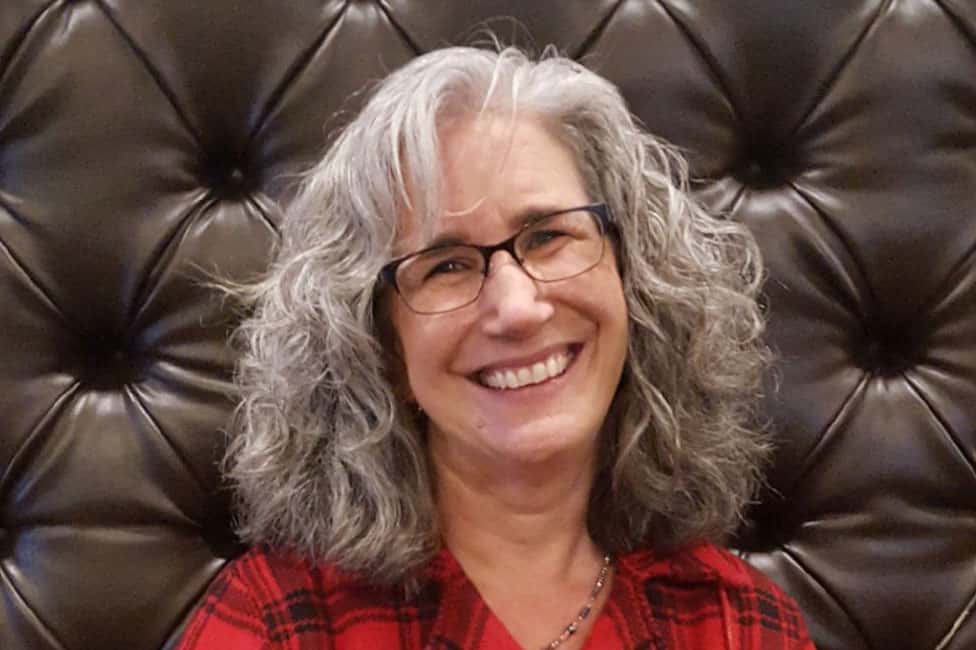 woman smiling wearing plaid red shirt and glasses