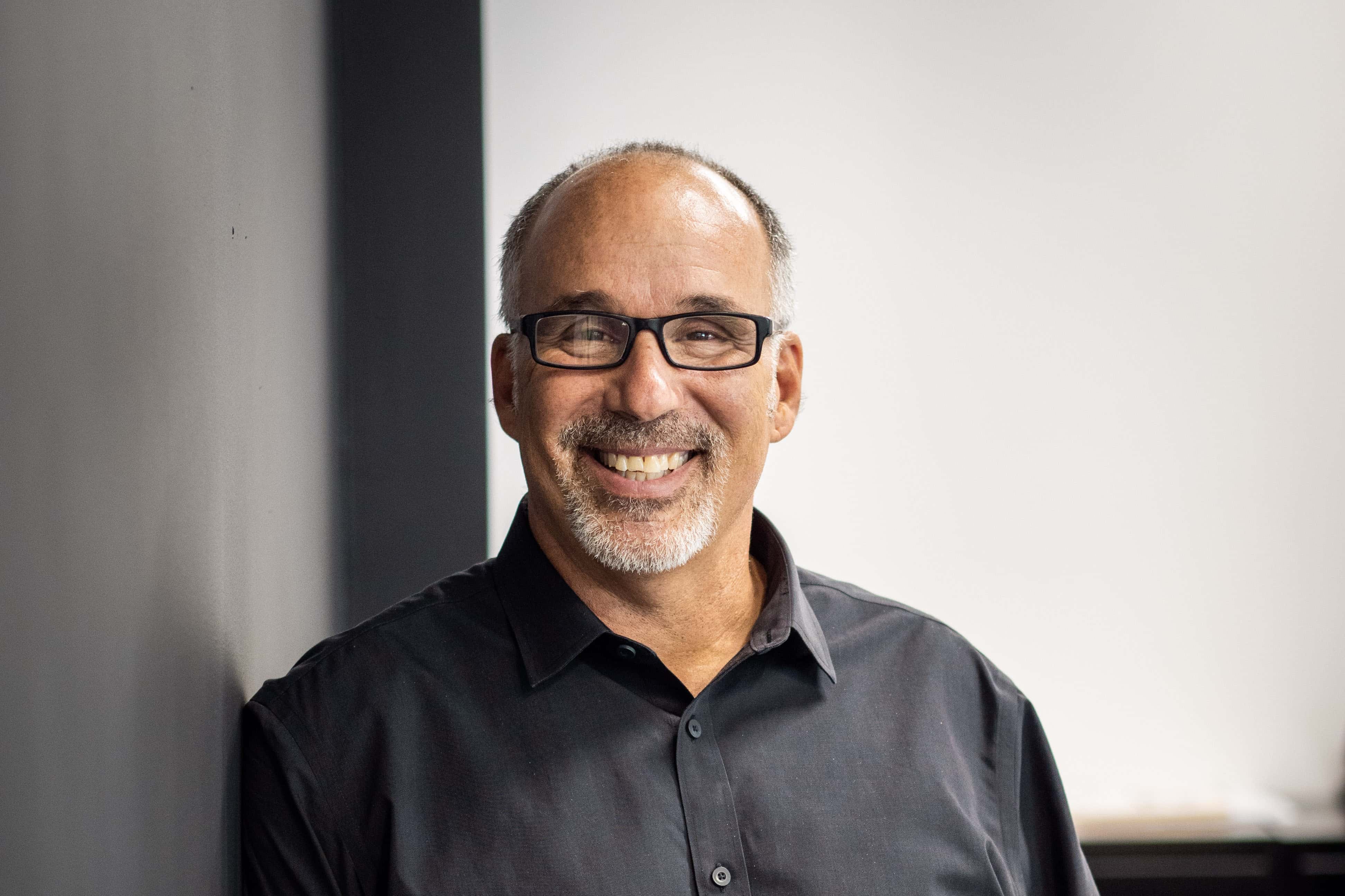 man smiling wearing glasses and gray shirt