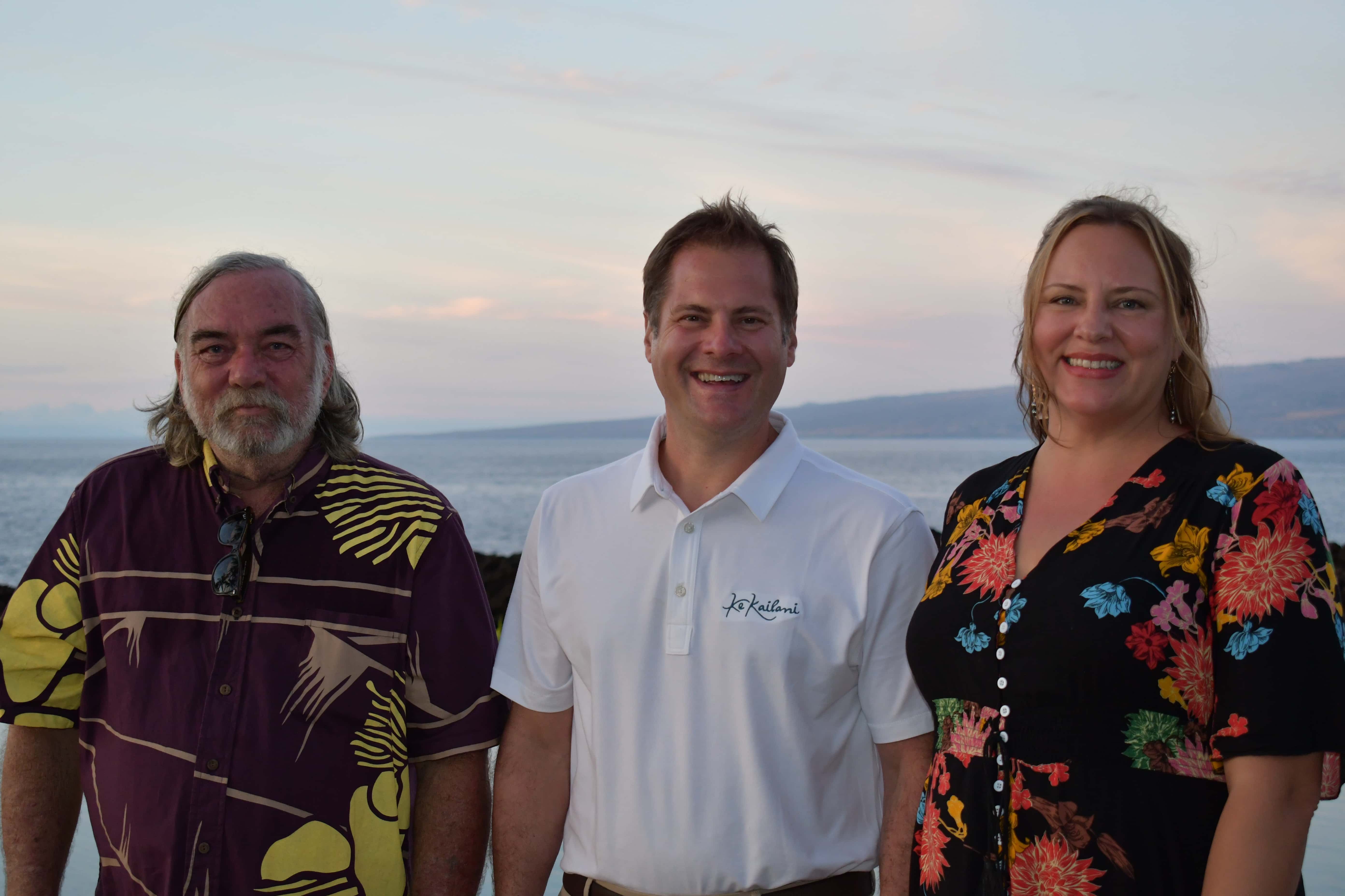 three people standing in front of ocean