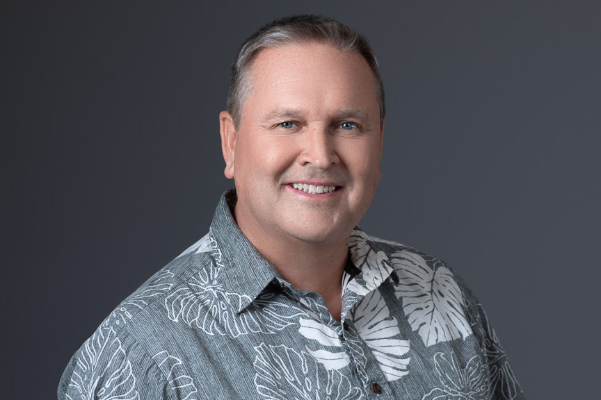 man smiling in gray floral button up shirt